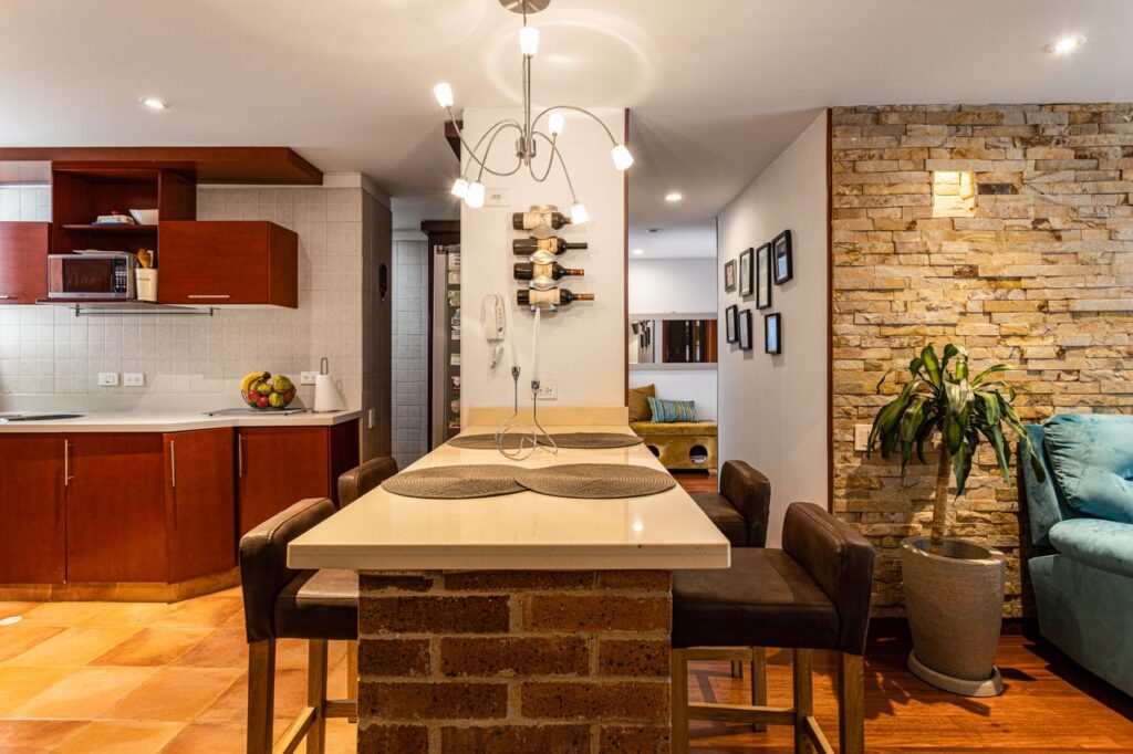 Stylish kitchen and living area with brick island and lighting in a Bogotá apartment.